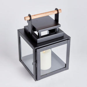 black metal lantern with glass sides and wood handle on the top of the lantern