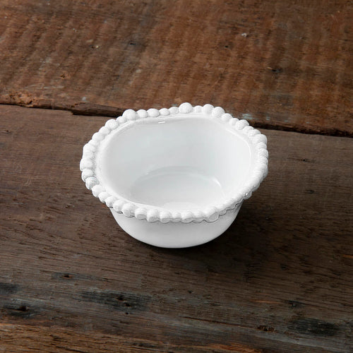 small white bowl with beaded rim sitting on a wood table