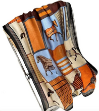 Load image into Gallery viewer, A folded silk scarf featuring a patchwork design with illustrations of horses in orange, brown, light blue, and beige blocks, displayed on a white background.
