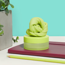 Load image into Gallery viewer, Speks Blur Calming Focus Putty in light green sitting on a desk with a notebook, a pencil and a potted plant

