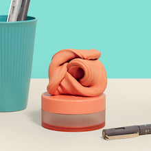 Load image into Gallery viewer, Speks Blur Calming Focus Putty in orange sitting on a desk
