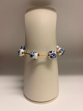 Load image into Gallery viewer, Bracelet with blue and white ceramic beads on a beige stand
