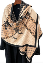 Load image into Gallery viewer, A beige and black patterned shawl draped over a black dress form on a wooden hanger, featuring geometric lattice designs and checkered borders.
