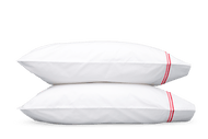Two pillows with Matouk Essex pillowcases with two simple lines of embroidery in Hibiscus red/pink, one line a slightly lighter shade than the other
