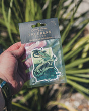 Load image into Gallery viewer, image of a hand holding an air freshener with image of gator catching a bird
