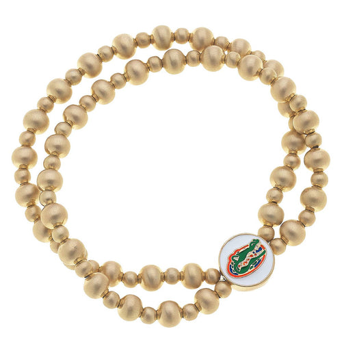 Two strand gold bead bracelet with round white enamel charm with gator head logo