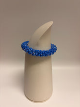 Load image into Gallery viewer, Blue beaded bracelet on a white cylindrical stand against a beige background
