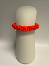 Load image into Gallery viewer, Red beaded bracelet on a gray cylindrical stand against a gray background

