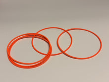 Load image into Gallery viewer, Two orange rubber bands on a beige background

