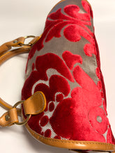 Load image into Gallery viewer, Red floral patterned bag with brown leather strap on a light background
