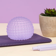 Load image into Gallery viewer, purple stress ball with texture sitting on a notebook
