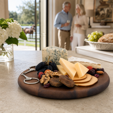 Load image into Gallery viewer, person holding the Vagabond House Cheese Board with Equestrian Bit accent set with cheese and fruit
