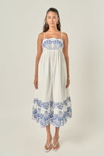 Load image into Gallery viewer, person wearing a midi length white dress with blue embroidery at the bust and hem showing the dress length, scalloped bust and thin straps 
