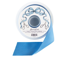 Load image into Gallery viewer, A spool of Hester &amp; Cook Fancy China Blue Ribbon with a single ribbon tail unspooled, shown on a clean white background.
