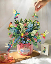 Load image into Gallery viewer, person touching on of the humming birds on the FreshCut Paper Hummingbird Oasis Pop-Up Greeting Card
