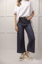 Load image into Gallery viewer, person wearing Jake Wide Leg Pants, wide leg blue jeans with white shirt and sneaker front view 
