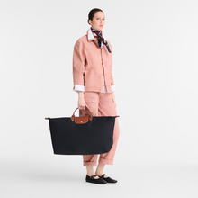 Load image into Gallery viewer, person holding the Longchamp Le Pliage Original X-Large Travel Bag in black by the two handles 
