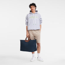 Load image into Gallery viewer, person holding the Longchamp Le Pliage Original X-Large Travel Bag in navy by the two handles 

