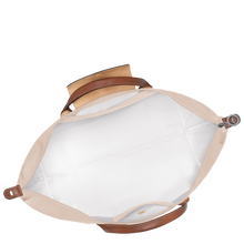 Load image into Gallery viewer, person holding the Longchamp Le Pliage Original X-Large Travel Bag in paper open to show white interior 
