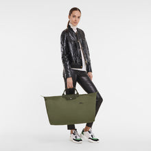 Load image into Gallery viewer, person holding Longchamp Le Pliage Green/Recycled X-Large Canvas Travel Bag in the color Forest with green leather
