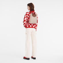 Load image into Gallery viewer, person wearing the Folded Longchamp Le Pliage Lid Medium Original Backpack in the color Paper with brown leather accents 
