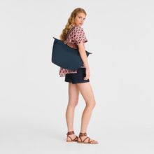 Load image into Gallery viewer, person with Le Pliage Original Large Shoulder Tote Bag in the color navy carrying with handle resting on her shoulder
