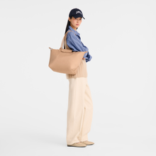 Load image into Gallery viewer, person holding the Longchamp Le Pliage One L Shoulder Bag Handbag in beige under her shoulder
