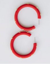 Load image into Gallery viewer, A pair of chunky red hoop earrings with small gold studs spaced along the outer edge, displayed on a clean white background.
