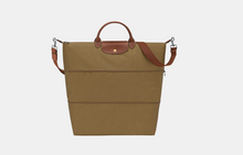 Load image into Gallery viewer, A structured tote bag in tan canvas with brown leather handles, a brown leather front tab, and a brown shoulder strap, shown on a light gray background.
