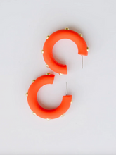Load image into Gallery viewer, A pair of chunky orange hoop earrings decorated with small gold studs, displayed on a clean white background.
