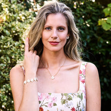 Load image into Gallery viewer, woman wearing gold chain necklace with mother of pearl flower shaped pendant and matching earrings and bracelet 
