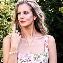 Load image into Gallery viewer, woman wearing gold chain necklace with mother of pearl flower shaped pendant and matching earrings and bracelet 
