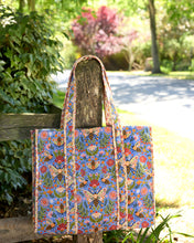 Load image into Gallery viewer, Printfresh Bee Tapestry Traveler Tote in a colorful print with bees. Bag is hung on a fence post 
