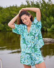 Load image into Gallery viewer, woman in the Printfresh Gator Grove Eco Satin Sweet Dreams Set in Blue Lagoon short sleeve button down top and short shorts
