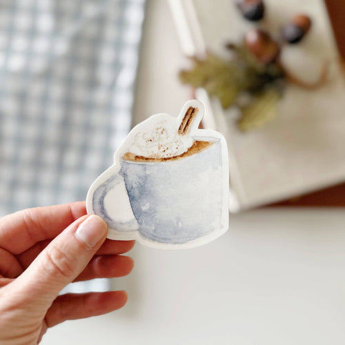 watercolor style sticker of a mug with whip cream and a cinnamon stick
