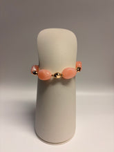 Load image into Gallery viewer, Bracelet with pink beads on a cylindrical stand against a neutral background
