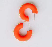 Load image into Gallery viewer, Bright orange crescent-shaped hoop earrings with small gold studs, shown on a plain white background.
