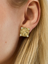 Load image into Gallery viewer, A close-up of a model's ear wearing a gold stud earring featuring an embossed bee design and four small white pearl accents.
