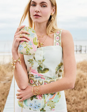 Load image into Gallery viewer, Woman in a floral dress holding a matching clutch on a beach.
