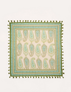 A square woven textile with a cream background, featuring a repeating paisley pattern in sage green and light blue. The edges are finished with a border of olive green tassels.