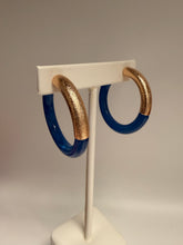 Load image into Gallery viewer, Gold and blue ring on a white stand against a gray background
