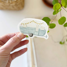 Load image into Gallery viewer, hand holding a blue and white camper trailer sticker in a watercolor style 
