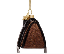 Load image into Gallery viewer, A Christmas ornament shaped like a small purse or pouch, with a glittery bronze-brown body, glossy black trim, silver feet, and a gold hanging chain with a star charm.
