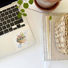 Load image into Gallery viewer, Wheelbarrow filled with flowers Sticker in a watercolor style on a computer
