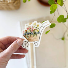 Load image into Gallery viewer, hand holding a Wheelbarrow filled with flowers Sticker in a watercolor style
