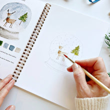 Load image into Gallery viewer, person painting a snowglobe in the Winter Watercolor Workbook
