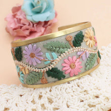 Load image into Gallery viewer, Decorative bracelet with floral patterns on a textured surface with flowers in the background
