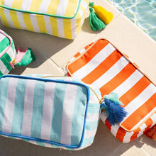 Load image into Gallery viewer, Megan Striped Cosmetic Bag in various colors sitting at the side of a pool
