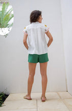 Load image into Gallery viewer, woman in the White Maya Embroidered Blouse paired in green shorts back view
