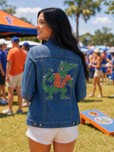 Load image into Gallery viewer, person wearing the University of Florida Full Gator Blue Denim Jacket at a gator event sparkiilng in the sun
